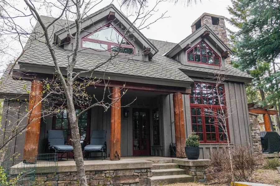 Gray craftsman-style home with log porch posts and red-framed windows among trees in Iron Horse