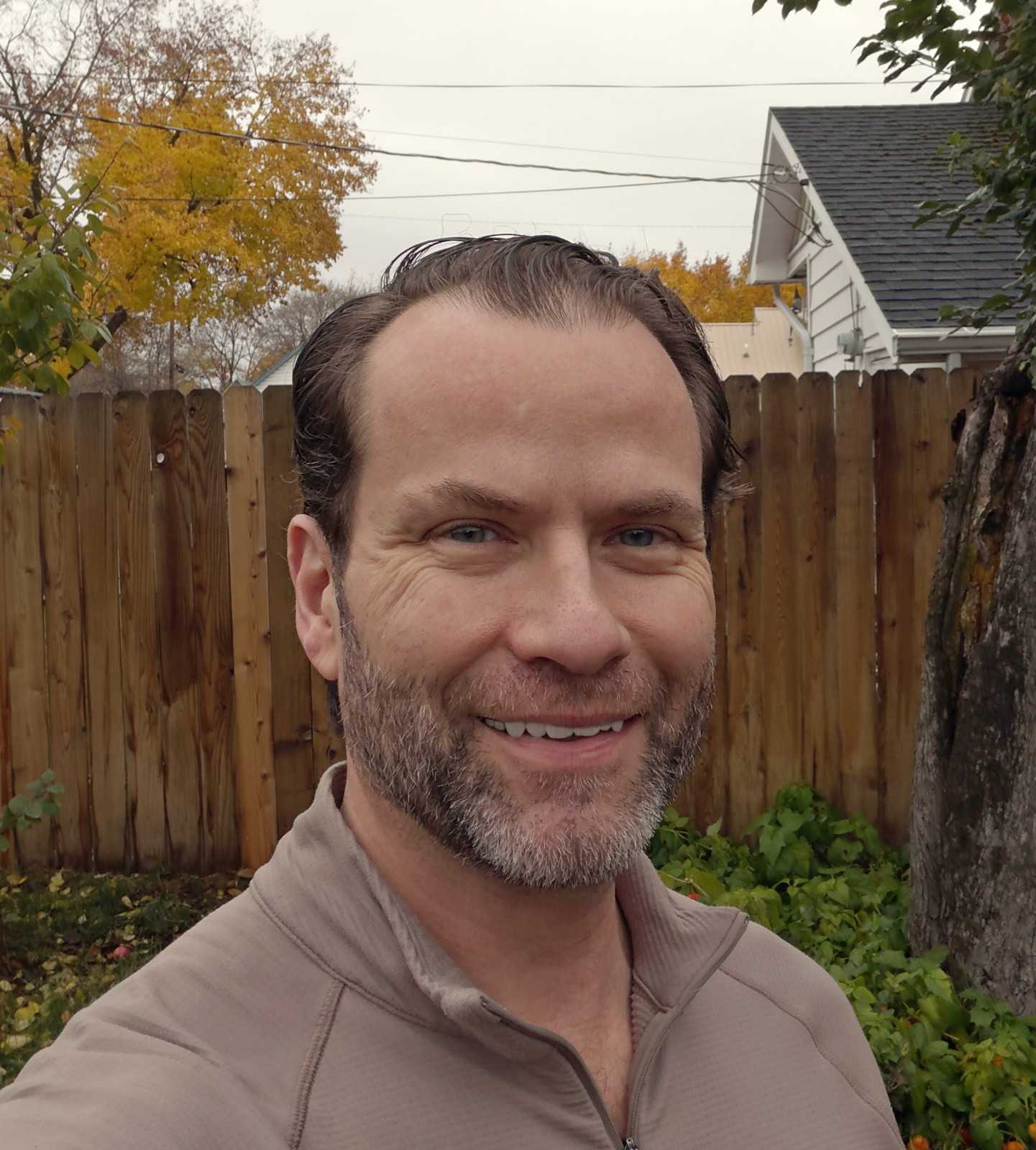 Ryan Berner smiling outdoors in a taupe quarter-zip on an overcast fall day.