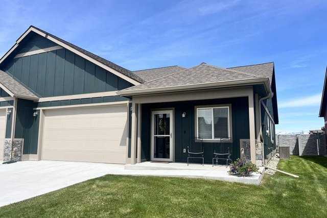 Dark green single-level home with a covered front porch and a two-car garage under a blue sky in Silverbrook Estates