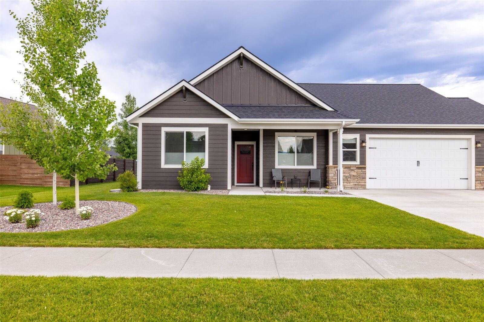 Single-level gray home with a red front door, a covered porch and a two-car garage behind a green lawn in Silverbrook Estates