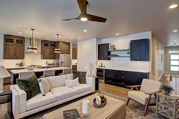 Open living room and kitchen with a ceiling fan, a sofa and dark wood cabinets in a Silverbrook Estates home