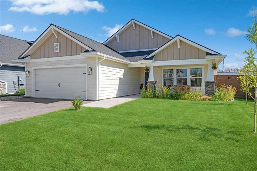 Tan craftsman-style home with a two-car garage, stone porch columns and a flower bed in Silverbrook Estates